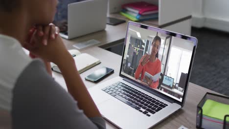 mid section of african american woman having a video call with female colleague on laptop at office