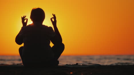 Senior-Woman-Meditates-In-A-Picturesque-Place-At-Sunset