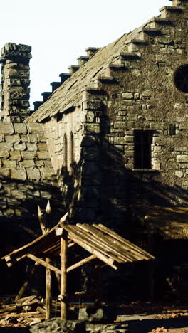 a close-up of a stone building with a thatched roof and a wooden frame in front of it.