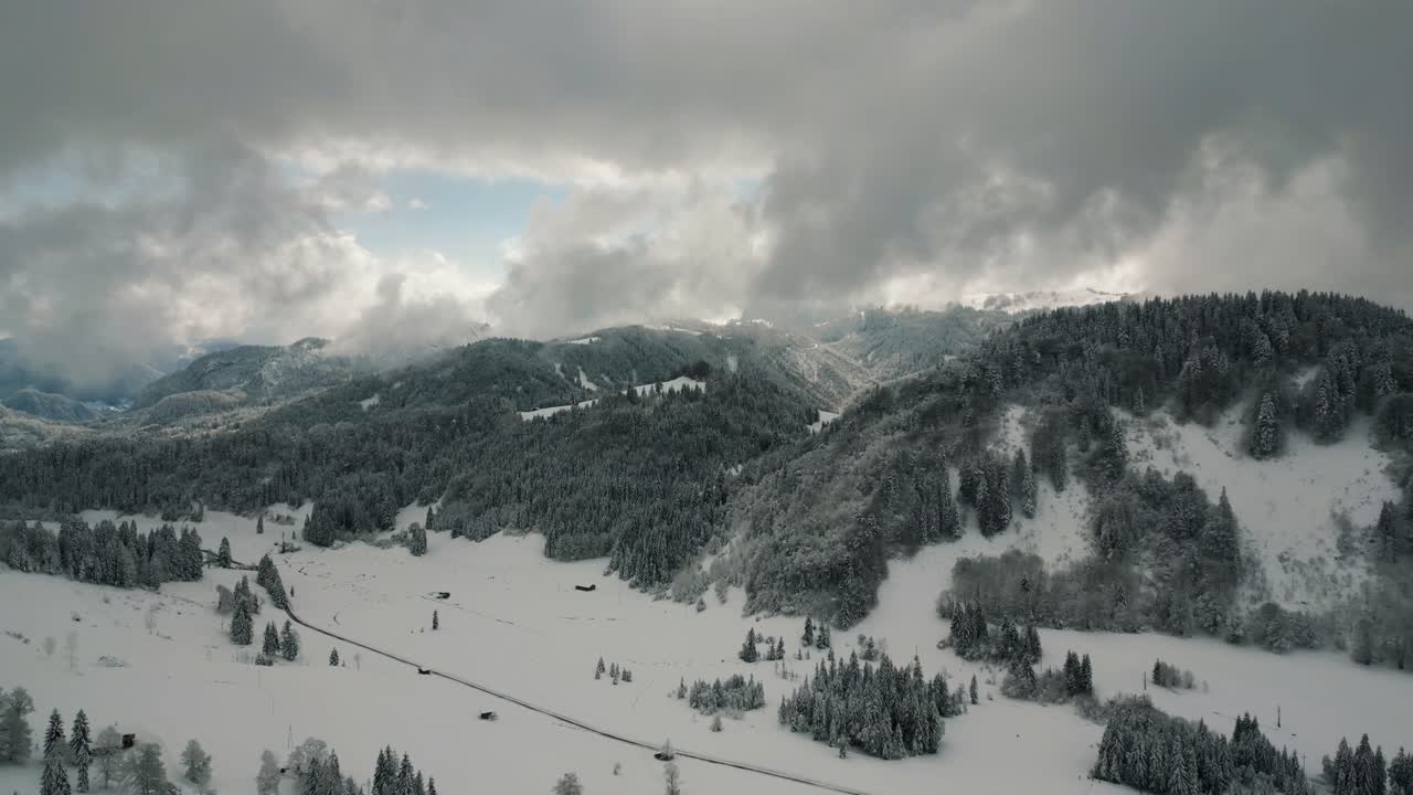나무와 눈이 있는 목가적인 눈 덮인 풍경의 구름에 있는 산봉우리