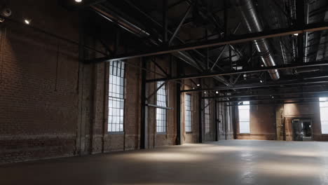 spacious empty industrial warehouse with brick walls and large windows
