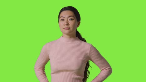 녹색 스크린 앞에 서 있는 자신감 넘치는 독립적인 여성의 스튜디오 초상화