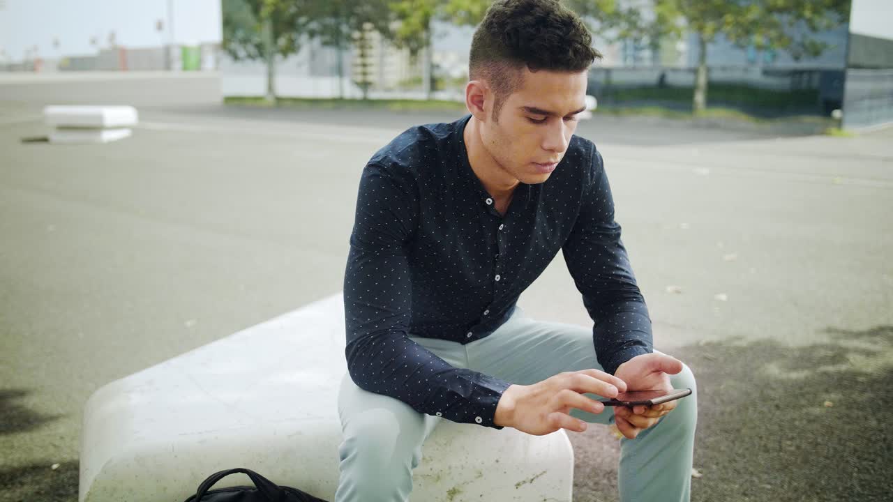 잘 차려입은 기업가 사업가의 초상 젊은 트렌디한 남자가 화창한 아침에 현대적인 도시 배경을 슬로우 모션으로 모바일과 상호 작용합니다.