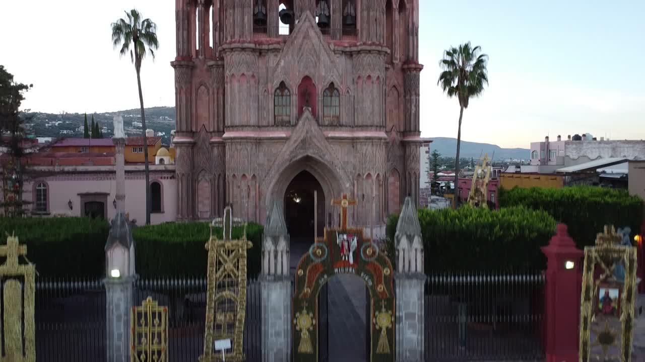 Aerial ascending shot of the church Parroquia de San Miguel Arc&aacute;nge in San Miguel De Allende in Mexico with view of the historic neo-gothic architecture and the colorful city in the background