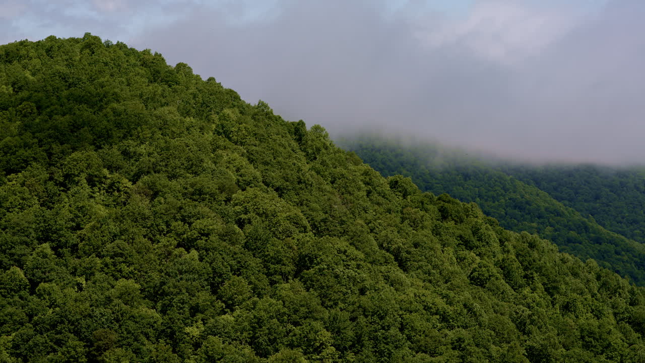 Drone floats above a vast mountain wilderness blurred by rain and rising fog