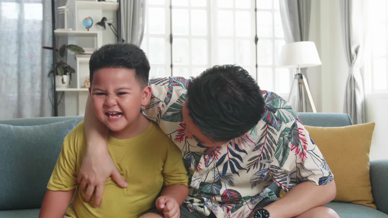 Happy Asian Father And His Son Are Watching Tv At Home. Family Time