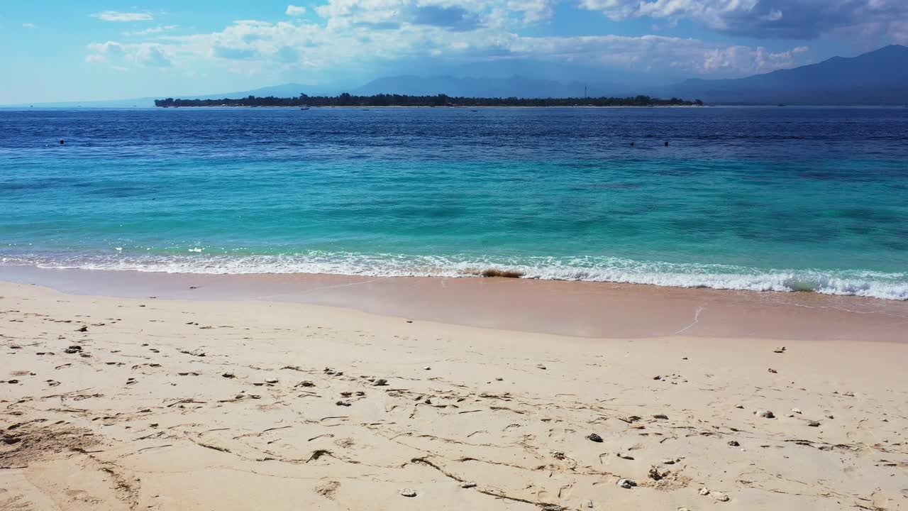 Playa tropical con arena blanca y montañas al fondo
