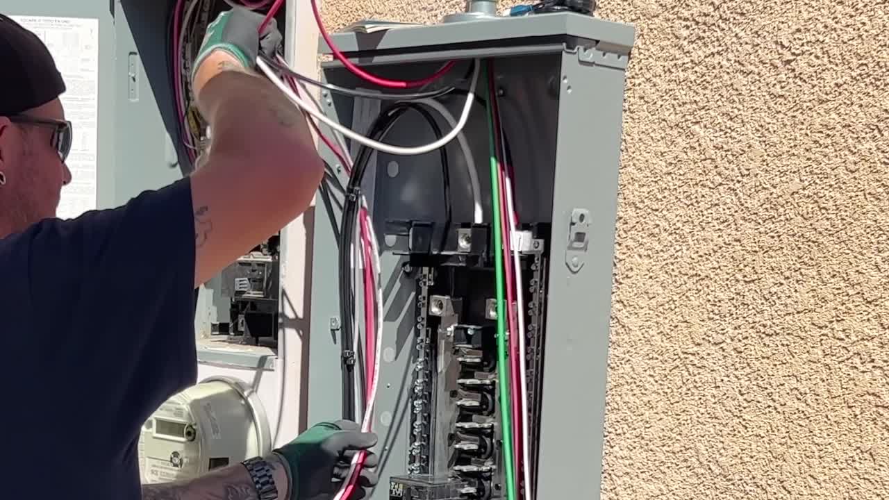 técnico colocando cables dentro de la caja de control del panel solar en el lateral de la casa para la instalación solar
