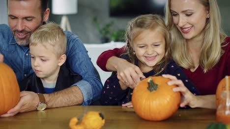 parents helping children in carving pumpkins