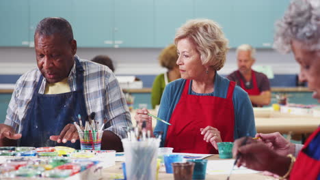 group of retired seniors attending art class in community centre with teacher