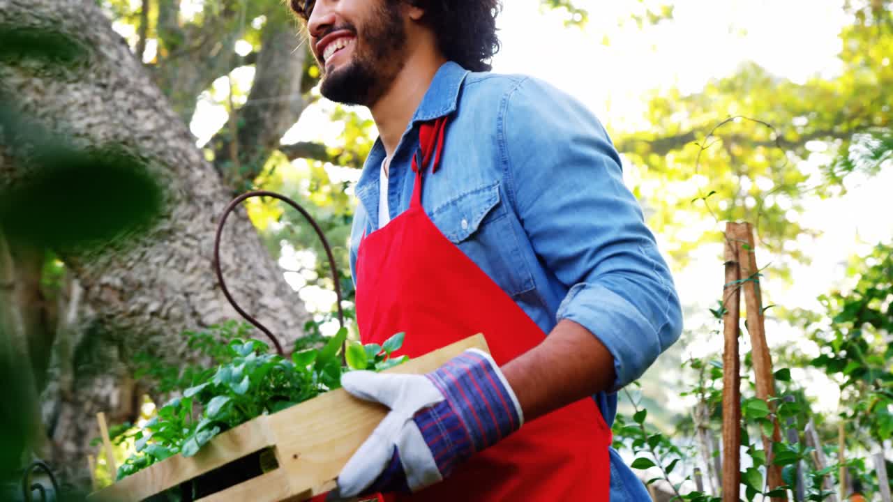 Jardinier transportant des plantes dans une caisse