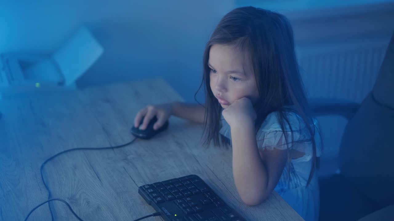 어린 소녀가 컴퓨터 앞에 앉아서 강한 감정을 표시합니다. 이 장면은 편안한 실내 환경에서 펼쳐지는 매력적인 순간 동안 그녀의 표현적 반응을 포착합니다.