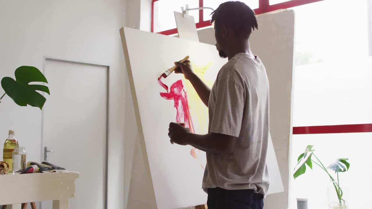 Artista uomo afroamericano che dipinge su tela nel suo studio d'arte.