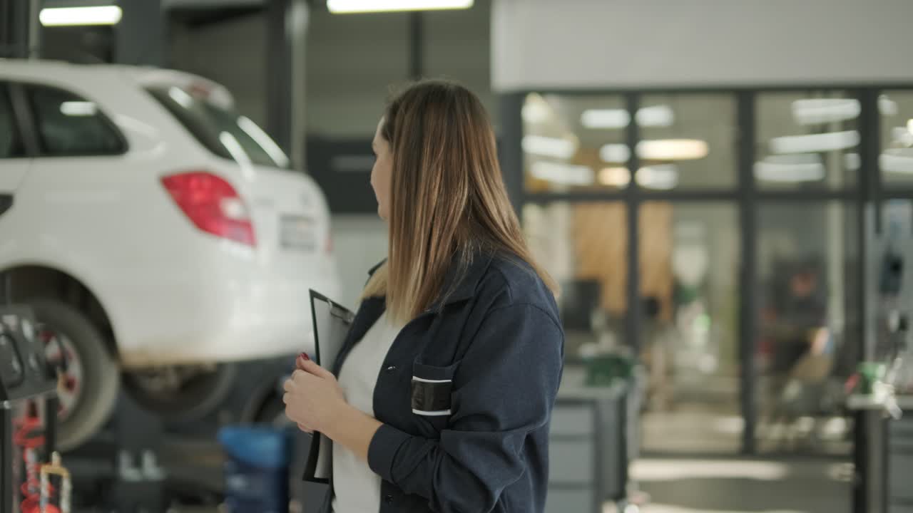 gerente femenina discutiendo la reparación de vehículos con el mecánico en el taller de reparación de automóviles