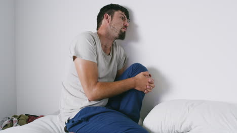 a paranoid creepy man sitting on a bed alone