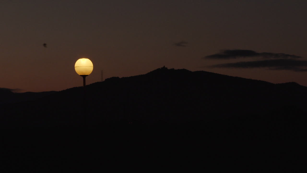 Sunset timelapse with a streetlight in the foreground and mountains in the background. The light comes on when it gets dark
