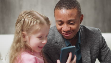 little child and carer man watch educative content via phone