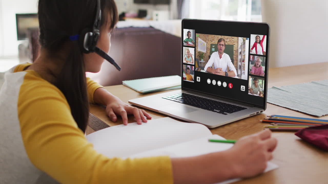 Schoolgirl using laptop for online lesson at home, with diverse teacher and class on screen