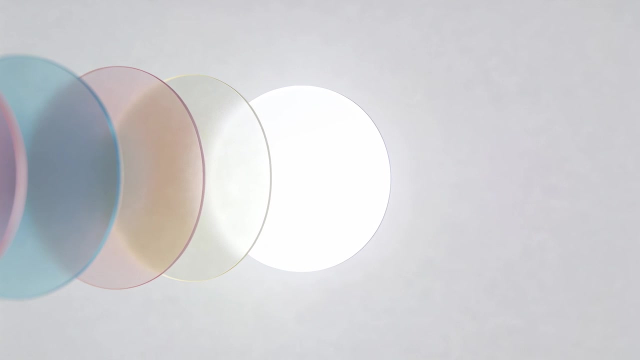 Sliding 4 tinted discs moving right across pale wall on playback crossing white light mixing colors