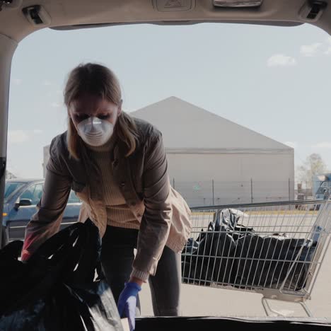 Woman-Puts-Bags-With-Purchases-From-The-Grocery-Store-And-Boxes-Of-Pizza-In-The-Car-Trunk