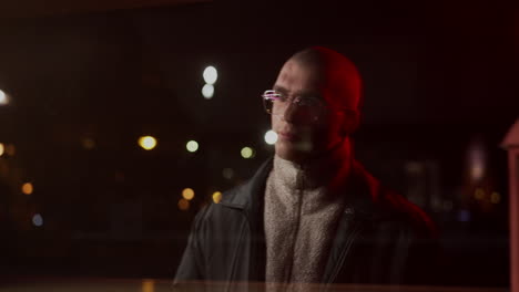 man looking out at city lights at night