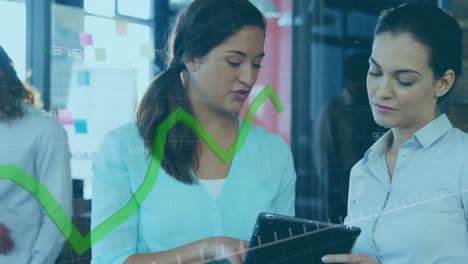 Animation-of-green-graph-moving-over-two-diverse-women-discussing-over-digital-tablet-at-office