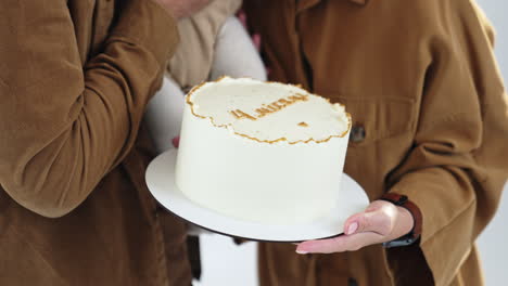 unrecognized couple with baby in hands and festive cake. family celebrating four months of a child. close up.