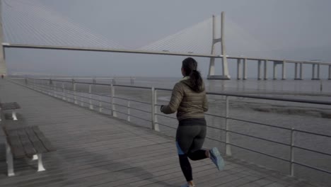 smiling brunette woman running on wooden jetty