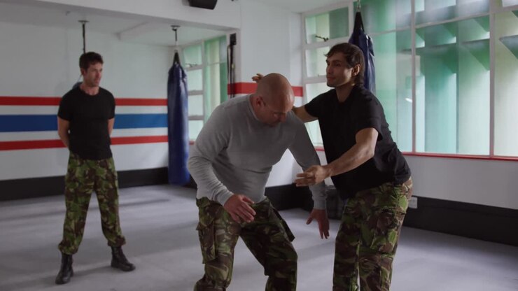 Caucasian man learning self defense from trainer in gym