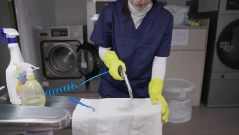 female worker drying towel after removing stain at laundry shop