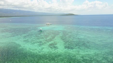 Aerial-view-by-drone-of-ocean-in-the-Philippines-with-traditional-banka-boat-and-mountain-in-the-background