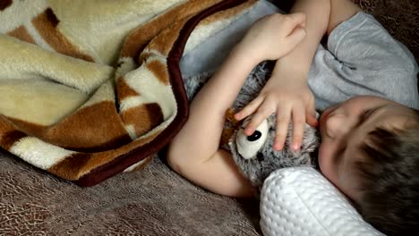niño durmiendo y acariciando a un oso de juguete