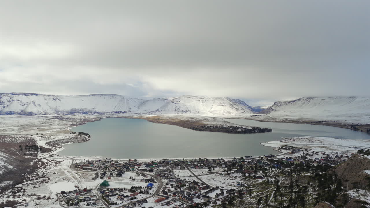 Snow-covered aerial view of Caviahue-Copahue town and lake in Neuquén, Argentina, surrounded by mountains in winter