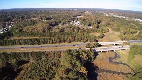 Interstate-camera-pan-and-retreat,-showing-cars-and-trucks-crossing-a-level-bridge-over-a-saltwater-estuary