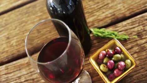 Glass-of-red-wine,-olives-and-rosemary-on-wooden-board
