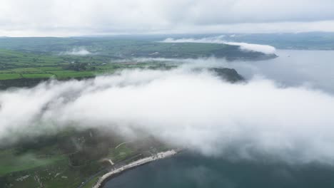 por encima de las nubes de irlanda del norte carretera costera cerca de la ciudad de glenarm con vistas al fascinante paisaje de la costa con mar tranquilo y carretera rocosa por la mañana
