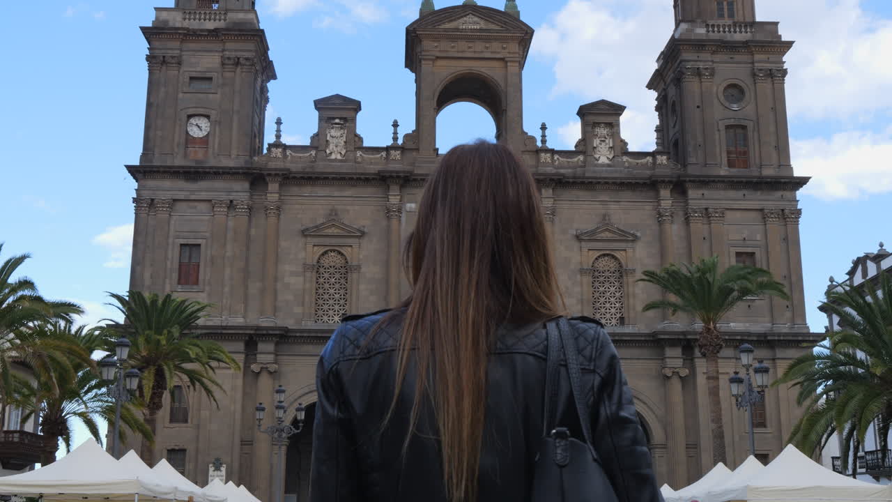 Slow motion video of a woman walking towards the cathedral of santa ana in vegueta, gran canaria
