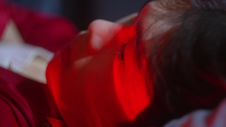 Primo piano del volto di una persona illuminato da luce rossa