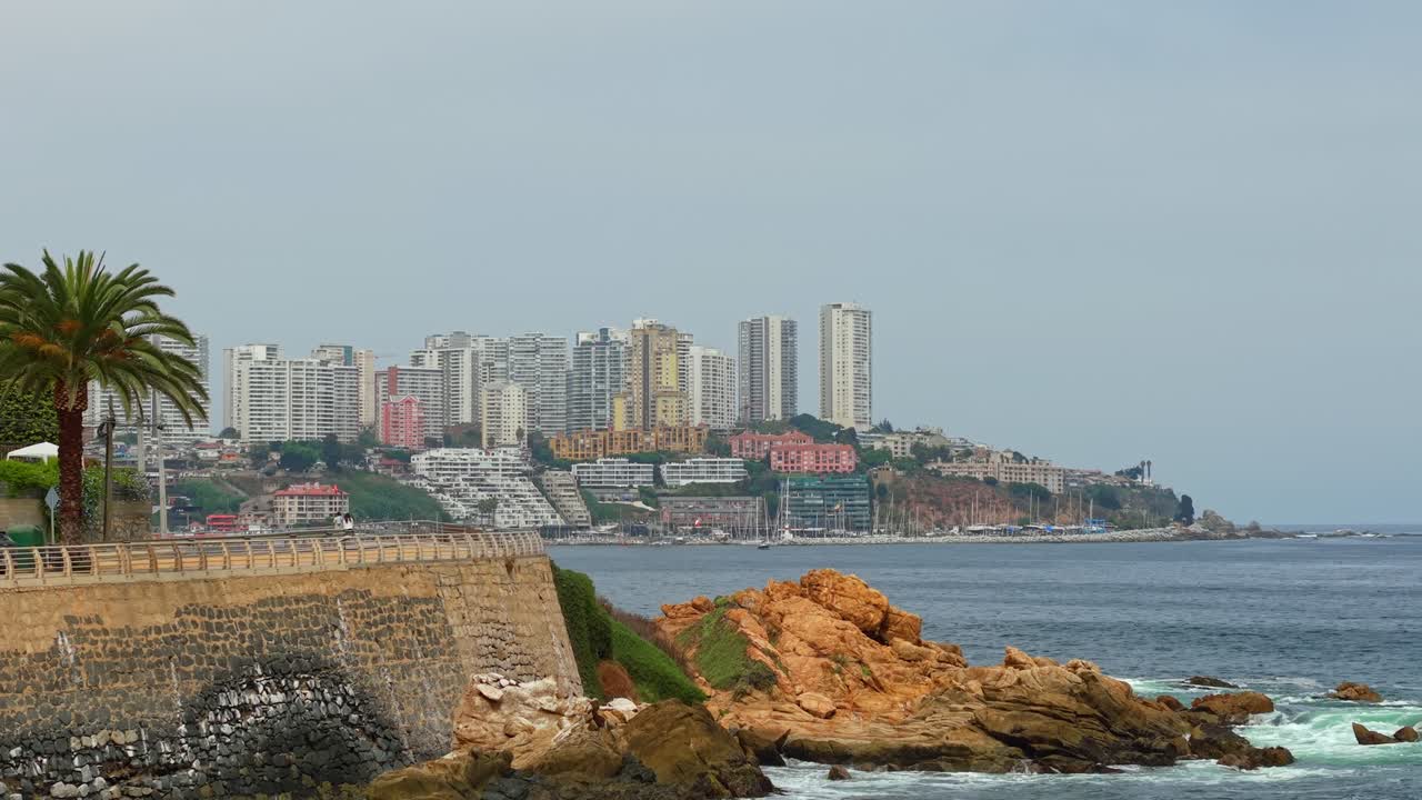 Dolly aereo sulla costa di Concón con gli esclusivi edifici della città costiera sullo sfondo, giorno nuvoloso, Cile