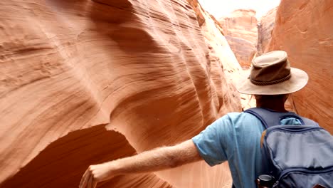 tracking shot man walking inside antelope canyon. young man hiking inside narrow canyon, walking in the arizona desert