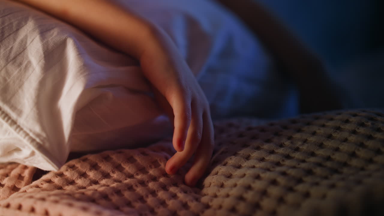 Girl hand touches plaid lying on pillow in white case on bed