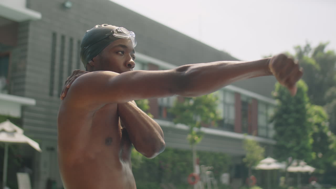 Black Athlete Stretching Wrists beside Swimming Pool