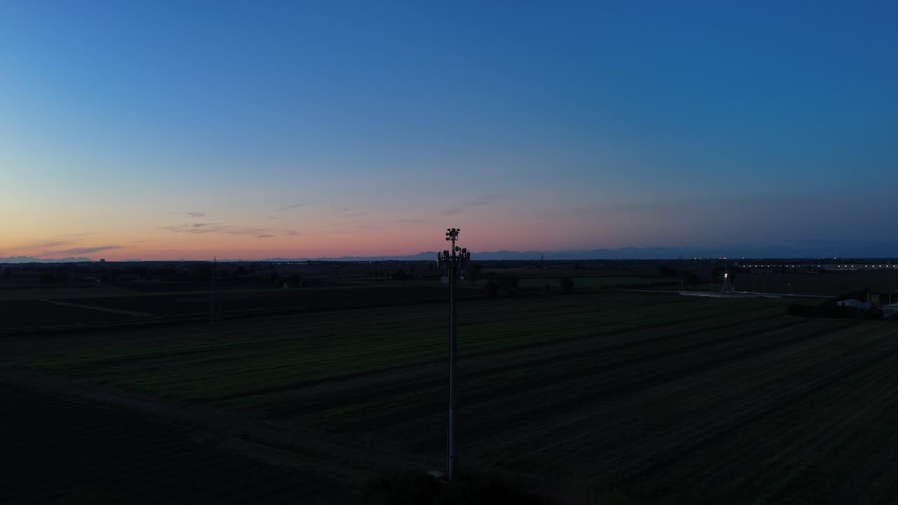 Silhouette di un traliccio per telecomunicazioni sullo sfondo di un cielo al tramonto, che fornisce copertura essenziale per la rete mobile e connettività digitale in un paesaggio agricolo rurale