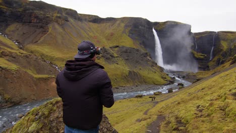 fpv pilot stands in canyon of haifoss waterfall in iceland and flies drone