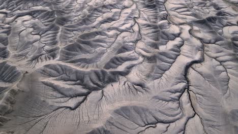 huge cracks in grey mountain surface, abstract dramatic nature panorama, aerial