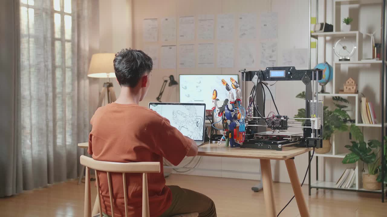 3d 프린팅으로 집에 있는 노트북에서 사이보그 손을 디자인하는 소년의 뒷면