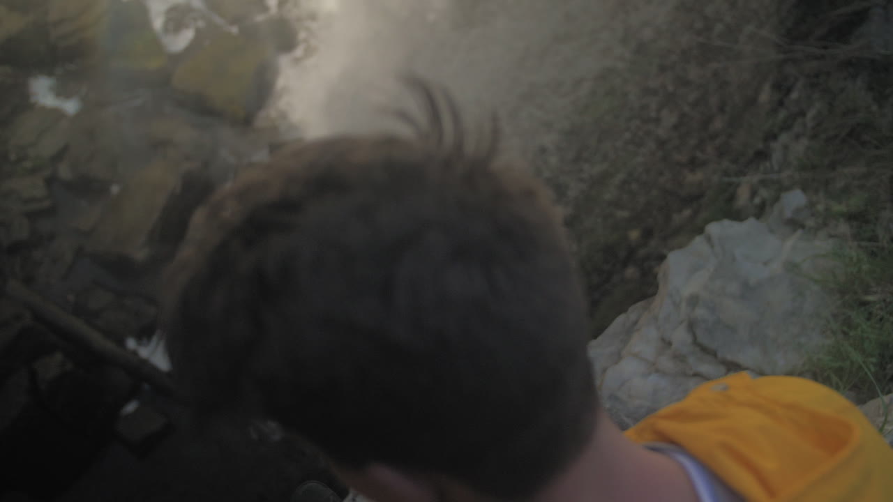 폭포의 가장자리에 정점을 찍는 백인 남자의 머리