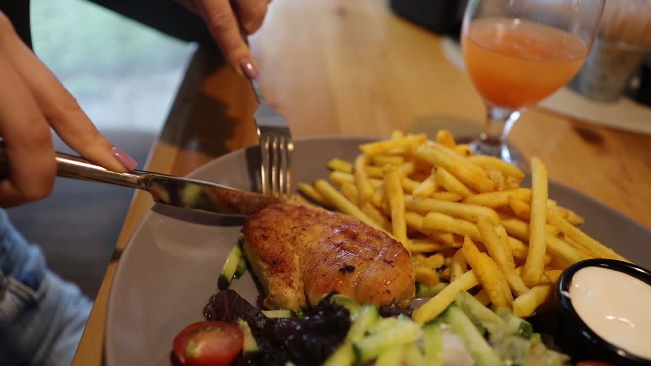 Close up of a woman cutting chicken dish in a restaurant