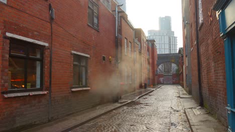 smoke from industrial building on alleyway in moss side, manchester, uk