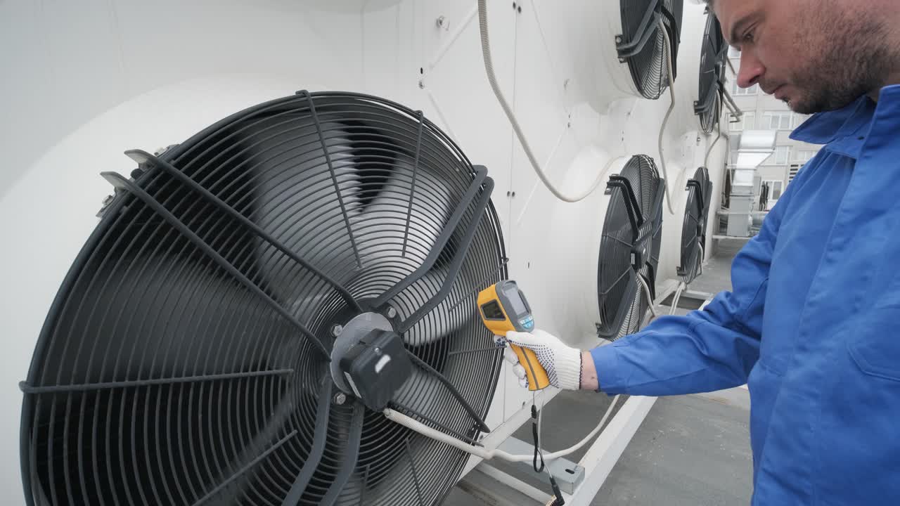 Technician uses a thermal imaging infrared thermometer to check the condensing unit heat exchanger